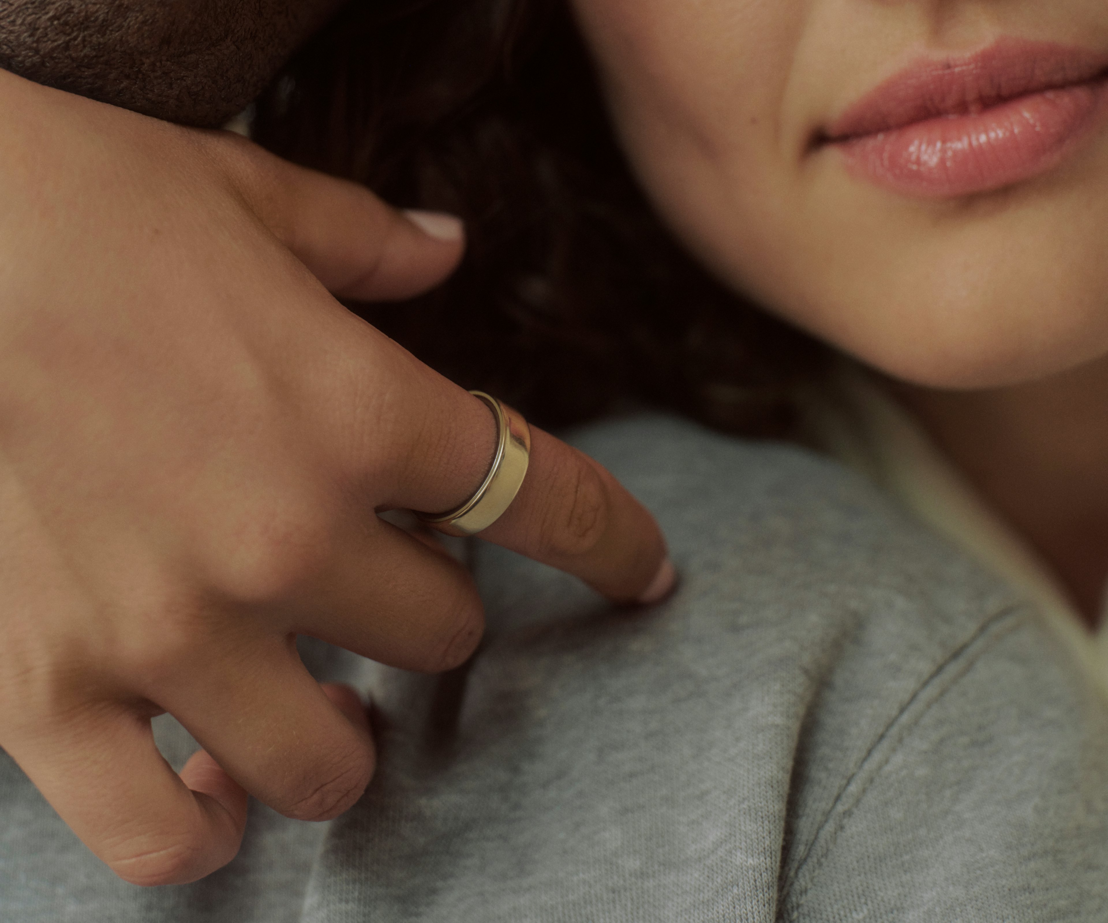 特写镜头：一只手佩戴 Gold Oura Ring 5，轻搭他人肩头。