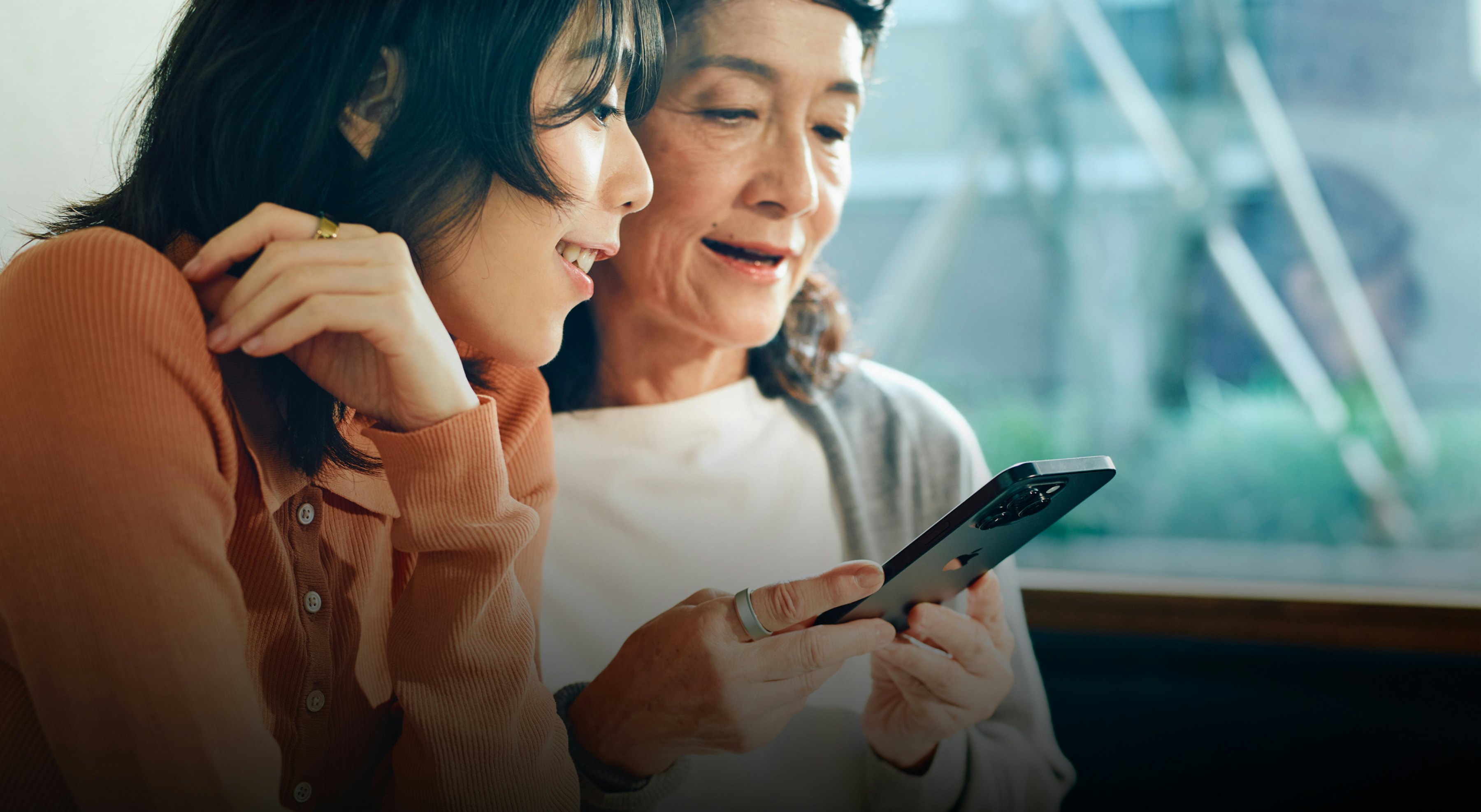 スマートフォンを見ているOura Ringを着用した2人の女性。