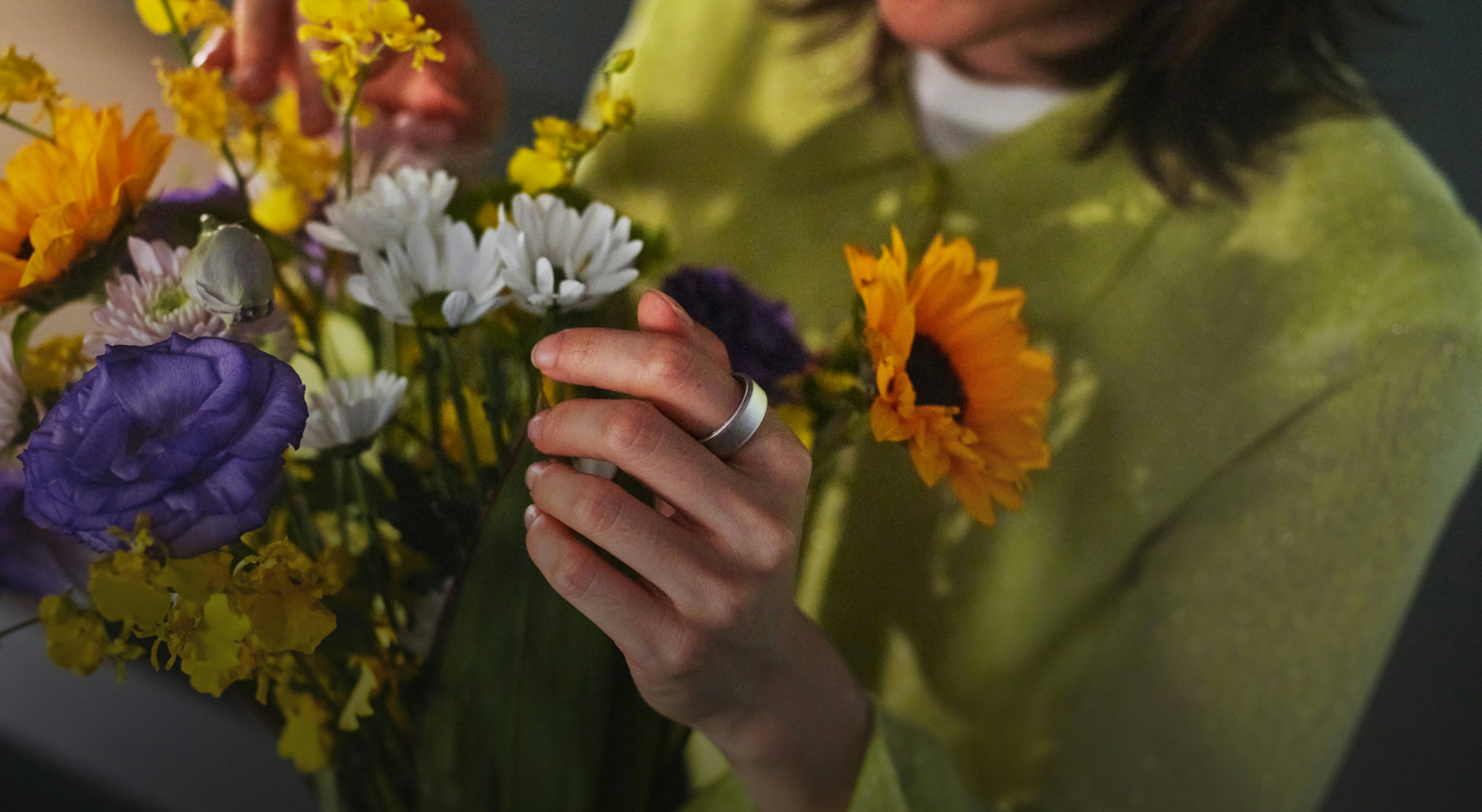 花を抱えているOura Ringを着用した女性の手のクローズアップ写真。