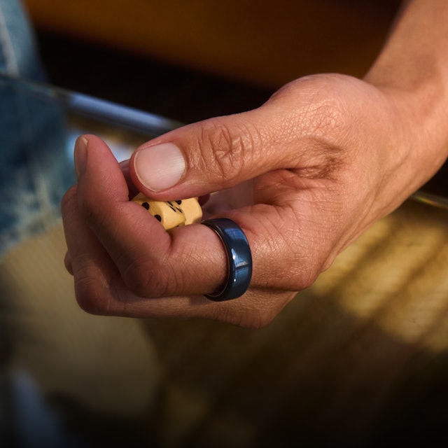 一個人手指上戴著 Midnight 色 Oura Ring 4 Ceramic 的手部特寫