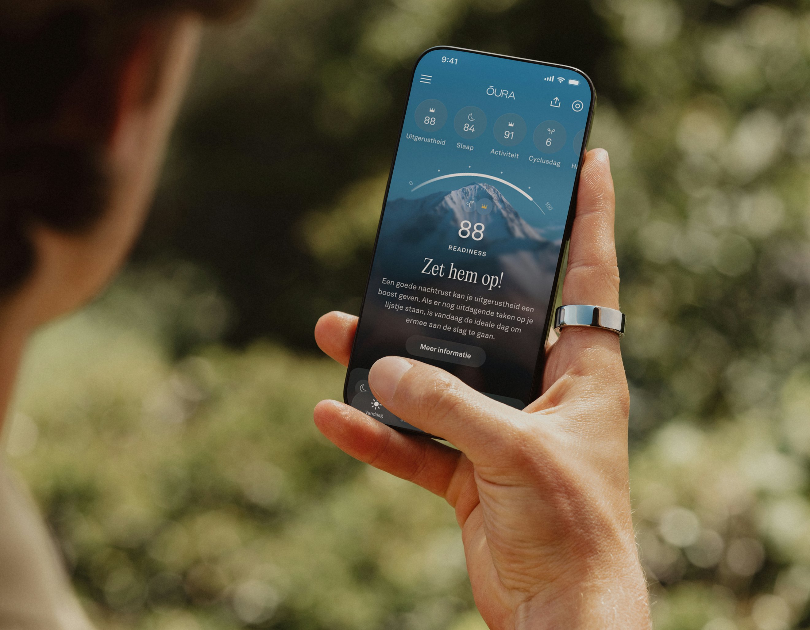 Iemand kijkt naar de Oura-app op een smartphone en draagt een Oura Ring om de rechterwijsvinger
